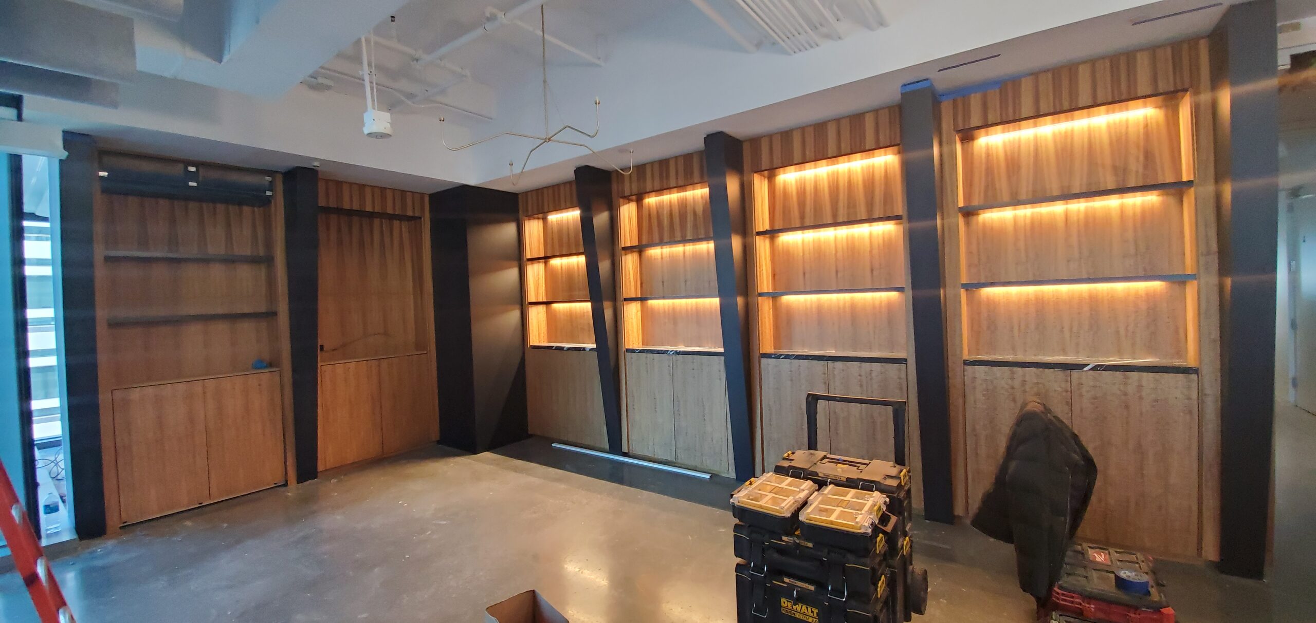 Modern interior showcasing wooden shelves with LED lighting, unfinished space, and tools for installation. Ideal for a design or renovation context.